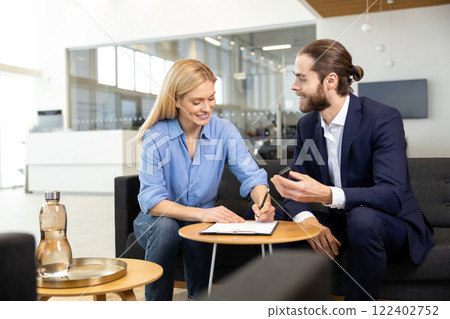 Blonde female customer signing the contract with dealership representative 122402752