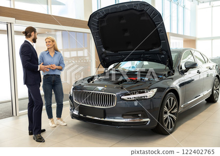 Dealership consultant showing the car to a female client Dealership consultant showing the car to a female client 122402765