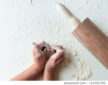 Childs hands playing with flour and rolling pin on white surface 122402789