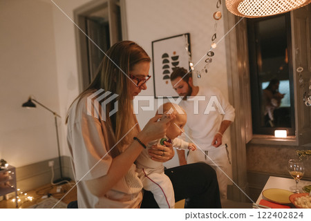 A Cozy Family Moment with Their Baby During a Peaceful Night Time at Home Together 122402824