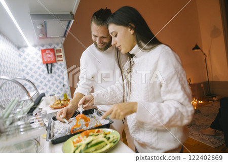 A couple is happily cooking together in a warm and inviting kitchen that is filled with love 122402869