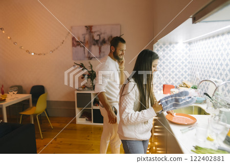 A couple happily cooking together in a modern, stylish kitchen filled with cheerful vibes 122402881