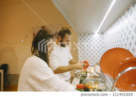 A couple cooks together in their modern kitchen, creating a delightful atmosphere 122402889