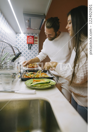 A couple enjoys a delightful cooking experience together in their modern, stylish kitchen A couple enjoys a delightful cooking experience together in their modern, stylish kitchen 122402901