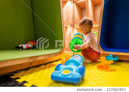 Child exploring activity toys and playing with a toy vacuum cleaner in a vibrant playroom Child exploring activity toys and playing with a toy vacuum cleaner in a vibrant playroom 122402903