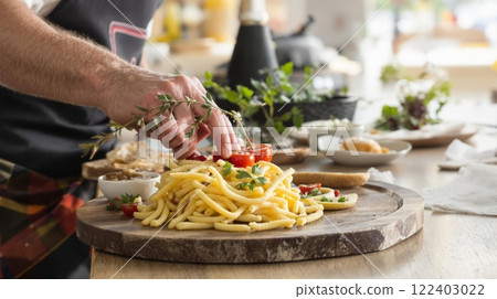 A chef is preparing fresh pasta with vibrant garnishes, showcasing culinary art and creativity 122403022