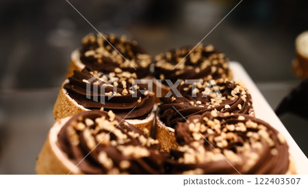 chocolate tart crushed peanut topping in buttery shortcrust pastry basket on white plate placed on counter perfect for dessert lovers indulgent treat rich texture sweet pastry close up festive 122403507