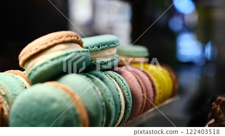 Close-up colorful macarons with white cream filling displayed under soft lighting on a countertop with a blurred background and selective focus highlighting their delicate texture and vibrant hues Close-up colorful macarons with white cream filling displayed under soft lighting on a countertop with a blurred background and selective focus highlighting their delicate texture and vibrant hues 122403518