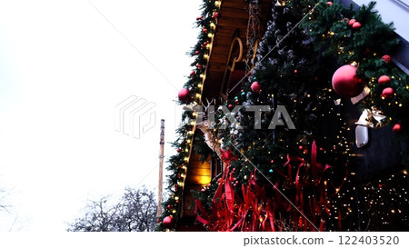 beautifully decorated entrance to home for Christmas holidays featuring reindeer figurine, red ornaments, and lush fir branches creating warm and festive atmosphere perfect for holiday celebrations 122403520