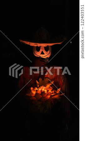 A Halloween character with a pumpkin body and a white skull-like face wearing a hat, red shirt, and sweater holds glowing autumn yellow leaves in hands, creating an eerie and festive atmosphere. 122403551