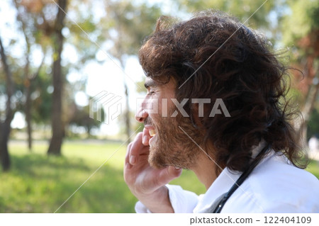 Long Hair Man Smiling Talking On The Phone Outside In The Park Long Hair Man Smiling Talking On The Phone Outside In The Park 122404109