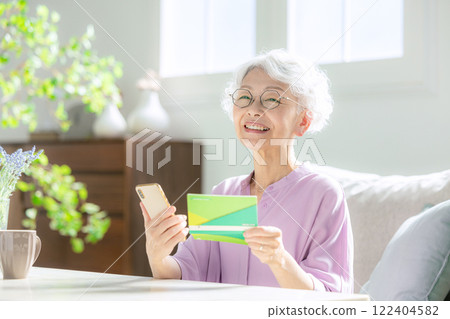 Senior woman looking at her smartphone and bankbook 122404582