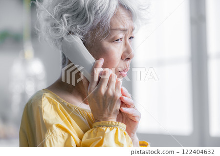 Senior woman talking on landline phone 122404632