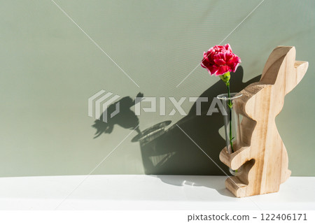 Minimalistic creative Easter concept. Two Easter bunnies under symbolic roof on green background. Celebration Easter holiday at home with family. Poster or greeting card 122406171