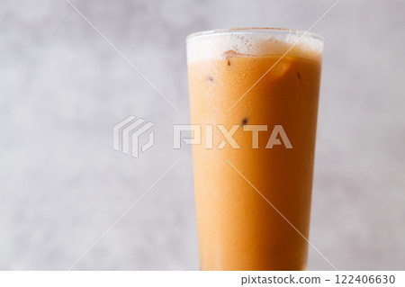 Iced Thai milk tea in a glass on wooden table. Iced Thai milk tea in a glass on wooden table. 122406630