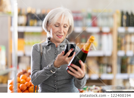 Elderly woman scanning qr code of champagne Elderly woman scanning qr code of champagne 122408194