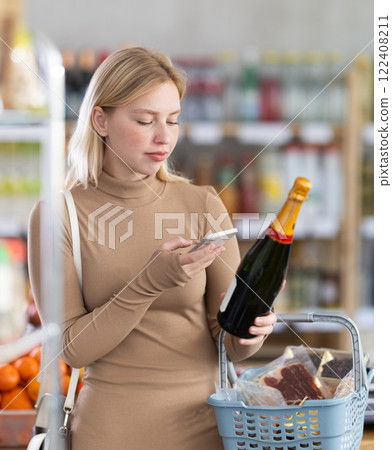 Young woman scanning qr code of champagne Young woman scanning qr code of champagne 122408211