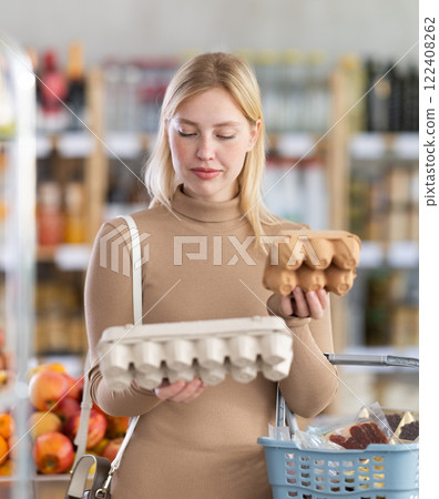 Girl buyer examine good, doubt and choose eggs in store 122408262