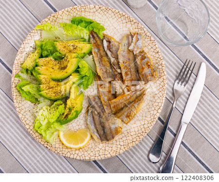 Fried cod fillet is guaranteed with salad of spinach leaves and avocado slices 122408306