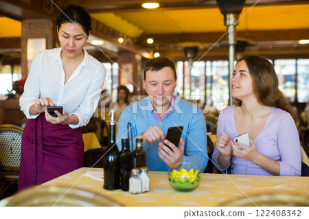Couple using smartphones to order food in restaurant 122408342