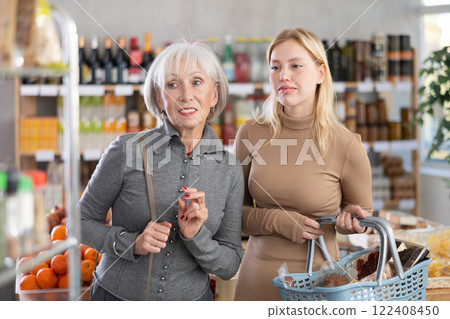 In store, young woman with grandma looking for something on shelf of showcase In store, young woman with grandma looking for something on shelf of showcase 122408450