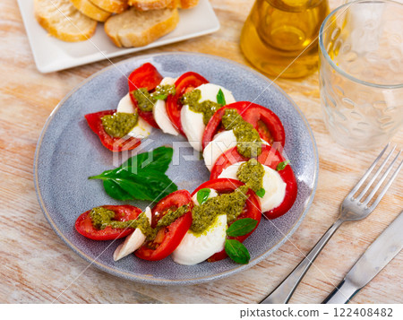 Caprese salad with tomatoes, mozzarella, basil, pesto 122408482