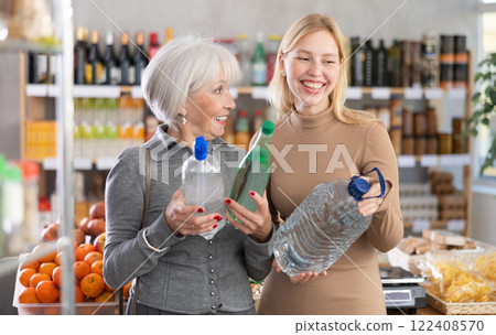 Mature mother and adult daughter buy bottles of spring water at supermarket 122408570
