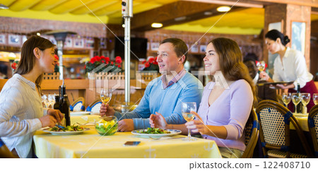 Man and two women eating and chatting in restaurant 122408710