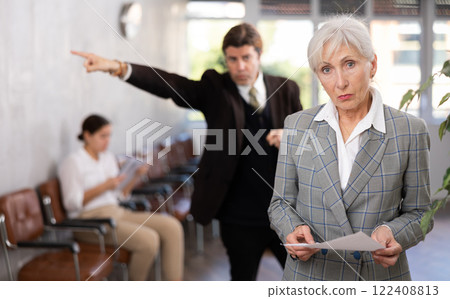 Puzzled woman with anxiety about target standing with hard copy version report near director s office 122408813