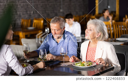 Elderly couple with adult woman having dinner in restaurant 122408833