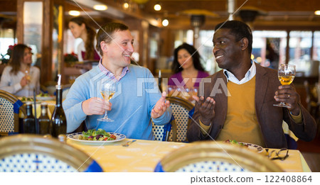 Two cheerful men having dinner in cozy restaurant Two cheerful men having dinner in cozy restaurant 122408864
