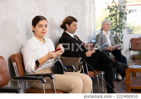 Young girl with phone waiting for job interview in office lobby 122408910