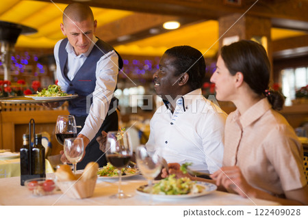 Waiter serving meals for couple at restaurant 122409028