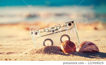Nostalgic scene with transparent cassette tape and seashells on sparkling beach sand 122409029
