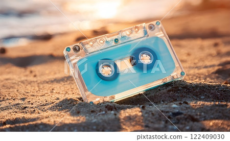 A nostalgic scene of a transparent light blue cassette tape, sand and a sparkling beach at dusk 122409030