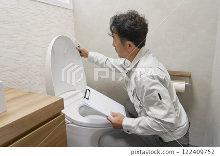 A repairman checking a toilet malfunction A repairman checking a toilet malfunction 122409752