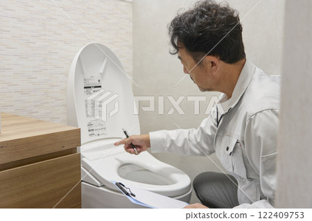 A repairman checking a toilet malfunction A repairman checking a toilet malfunction 122409753