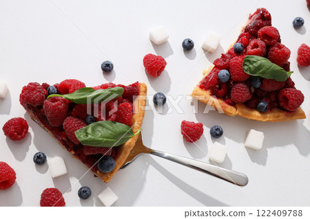 Pieces of berry pie, sugar and berries on white background, top view Pieces of berry pie, sugar and berries on white background, top view 122409788