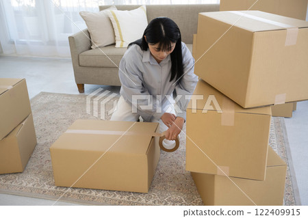 Young woman packing cardboard boxes for moving Young woman packing cardboard boxes for moving 122409915