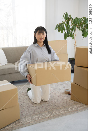 Young woman packing cardboard boxes for moving Young woman packing cardboard boxes for moving 122409929