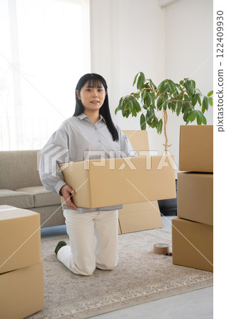 Young woman packing cardboard boxes for moving Young woman packing cardboard boxes for moving 122409930