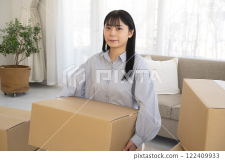 Young woman packing cardboard boxes for moving Young woman packing cardboard boxes for moving 122409933