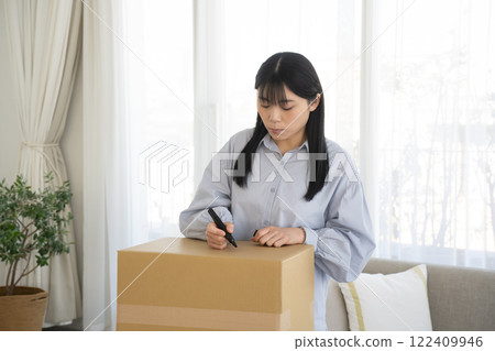 Woman writing on cardboard box with marker Woman writing on cardboard box with marker 122409946