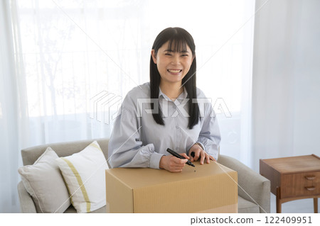 Woman writing on cardboard box with marker 122409951