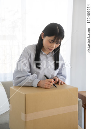 Woman writing on cardboard box with marker Woman writing on cardboard box with marker 122409954