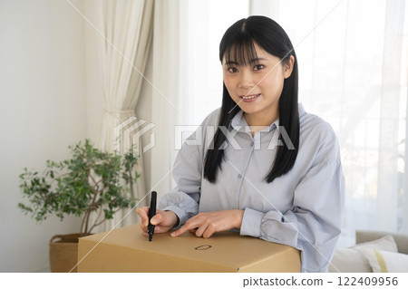 A woman drawing illustrations on a cardboard box with a marker 122409956