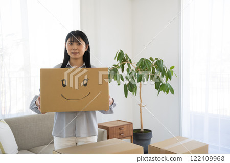 A woman holding a cardboard box with a smiling face illustration on it 122409968