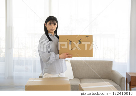 Woman holding a cardboard box with an illustrated face Woman holding a cardboard box with an illustrated face 122410013