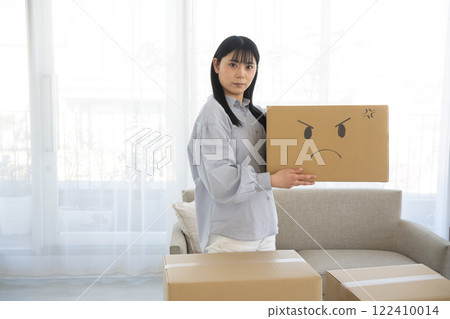 Woman holding a cardboard box with an illustrated face Woman holding a cardboard box with an illustrated face 122410014