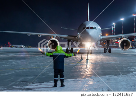 Airliner marshalling at the aiport apron at winter night. Passenger aircraft meeting Airliner marshalling at the aiport apron at winter night. Passenger aircraft meeting 122411687